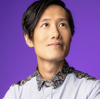Portrait of Hugh Hou, smiling and looking up, against a purple background