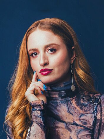 Portrait of Keeley Turner, with long copper hair, against a navy background